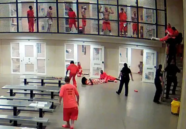 A video still from a surveillance camera that captured the attempted suicide, and inmates' and deputies' save, to the right of the image at the top of the stairwell. At that moment, the inmate is being brought back over the railing. 