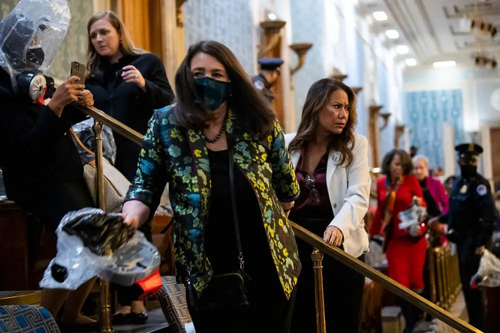 Reps. Diana DeGette, D-Colo., center, and Veronica Escobar, D-Texas, right, take cover as protesters disrupt the joint session of Congress to certify the Electoral College vote on Jan. 6, 2021. 