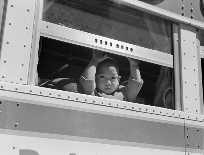 A Japanese-American child on the way to an 'assembly center' out of San Francisco before heading for a concentration camp, part of the internment of 110,000 Japanese Americans during World War II, at the order of Franklin Roosevelt. (Dorothy Lange)
