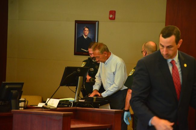 Assistant State Attorney Jason Lewis, in the foreground, who prosecuted the case, as David Zlokas is finger-printed in the background. (c FlaglerLive)