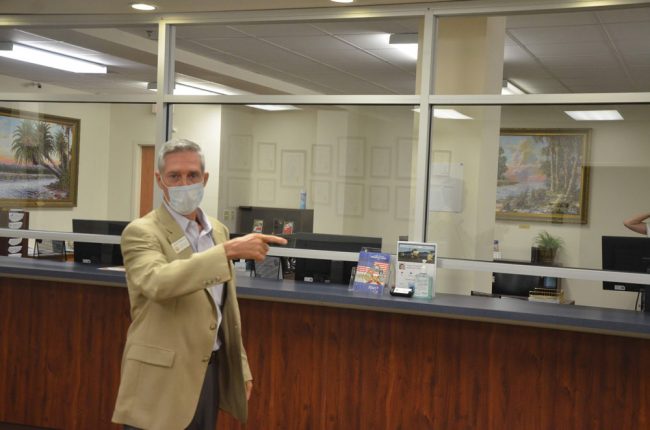 Jay Gardner, seen here in June, says the public is protected from exposure to the coronavirus from employees (and vice versa) since the office was equipped with counter-to-ceiling glass partitions. (© FlaglerLive)