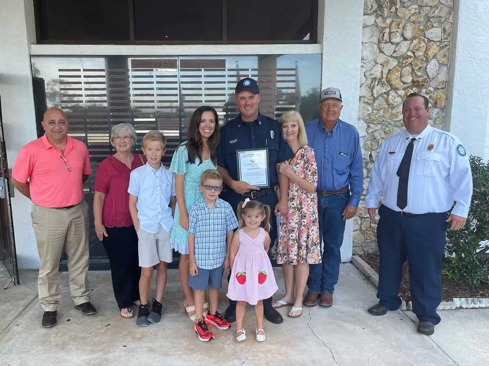 Palm Coast Fire Driver Engineer Jeremy Barton, holding the award, with his family, and, right, soon to be Fire Chief Kyle Berryhill. (Palm Coast)