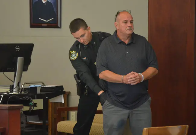 Flagler County Sheriff's bailiff Trevor Jacob searches Jerald Medders moments after sentence was pronounced and he was handcuffed this morning in a courtroom at the Flagler County courthouse. He was sentenced to 15 years in prison, but may be out in 12. (© FlaglerLive)