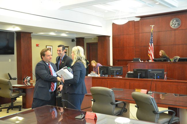 Defense attorney Josh Davis, left, shaking hands with Kayla Hathaway, the sheriff's office's attorney, after the hearing before County Judge Melissa Moore-Stens this afternoon. Assistant State Attorney Jason Lewis is to the right of Davis. (© FlaglerLive)