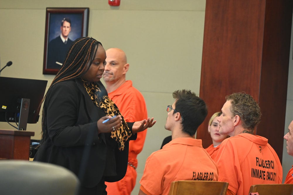 Assistant Public Defender Courtney Davison speaks with Joshua King, seated first from left, in court this morning. (© FlaglerLive)