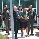 Eleven years after the original report of a rape, “we were able to get that final piece” of evidence, Sheriff Rick Staly said today of formner Palm Coast resident Kaivan Rahbar, “so we could put leg irons on this asshole and handcuffs.” Staly walked Rahbar to a patrol car that was to take him to the county jail this afternoon, hours after Rahbar was extradited from New York, where he had been living for six years. Staly was accompanied by, among others, Nicole Marsan, the lead detective on the case. (© FlaglerLive)