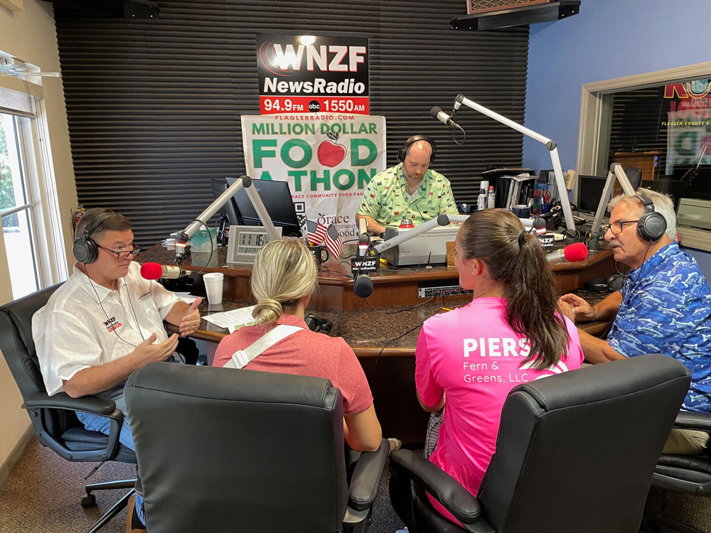 Flagler Broadcasting's Kirk Keller, left, will do most of the heavy lifting during the Food-A-Thon's four hours, with Grace Community Food Bank Director Charles Silano, right, helping. The WNZF photo above is from last year's Food-A-Thon.
