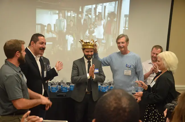 Angel Gonzalez is crowned winner of the 2016 Office Divvy Most Interesting Start-Up Contest for his Snappy Kraken company. He was flanked by Ky Ekinci (right), co-founder of Office Divvy with Lisa Ekinci (right), and judge and mentor (c FlaglerLive)