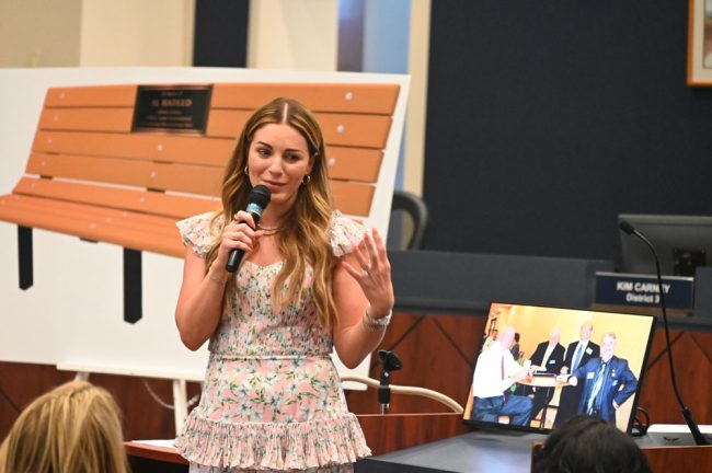 Kristen Hadeed speaks of growing up under Al's disciplinary aura, with a picture of the bench the county is dedicating to him at Princess Place Preserve. (© FlaglerLive)