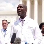 Dr. Joseph Ladapo, in an “America’s Frontline Doctors” lab coat, speaks at a July 2020 event that included Stella Immanuel, a doctor who said “demonic seed” causes ovarian cysts and endometriosis. (Screenshot from YouTube)