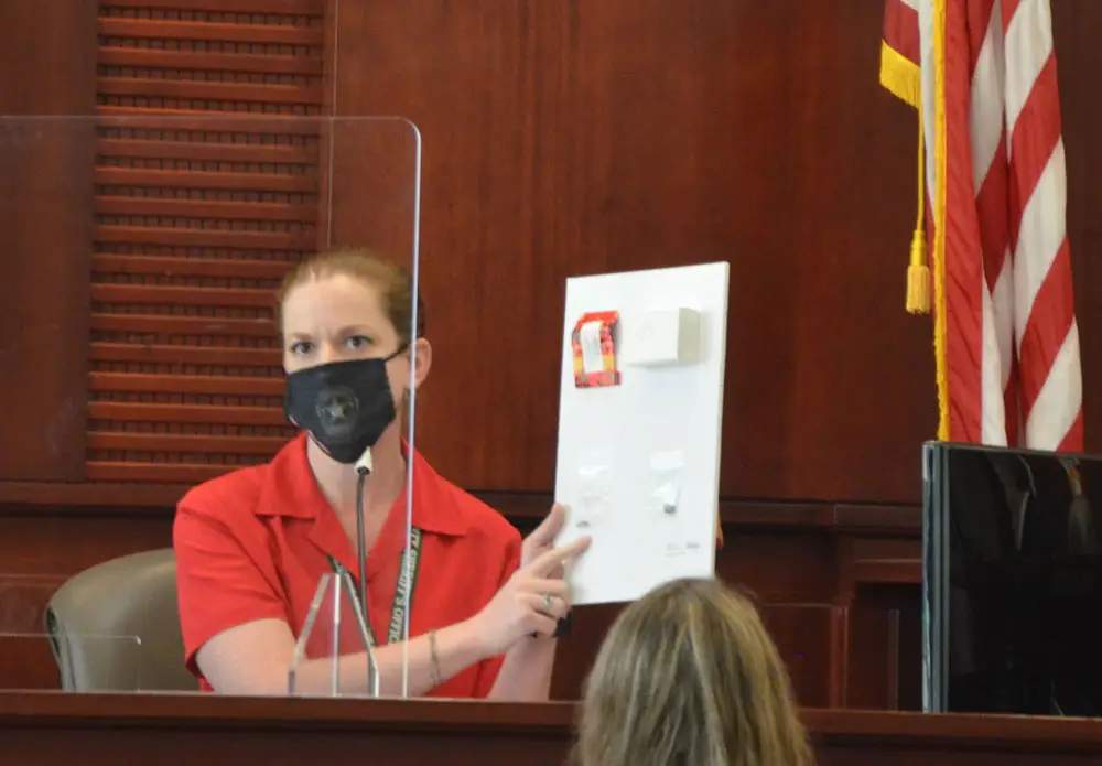 Lanie Rittenour, formerly a crime scene investigator, now a dispatcher with the Flagler County Sheriff's Office, shows the bullet fragments extracted from Elijah Rizvan's body during a brief testimony this morning--a rare moment of straight-forward testimony in a day dominated by three witnesses' fleeing and eluding attorneys' questions. (© FlaglerLive)