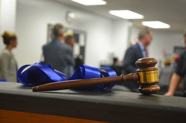 The judge's gavel in the mock courtroom built by Matanzas's construction flagship students for its law and justice flagship program, inaugurated Wednesday. The figures in the background are Superintendent Jim Tager and Matanzas Principal Jeff Reaves. (© FlaglerLive)