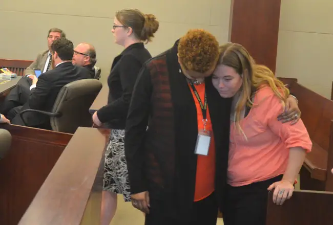 A victim's advocate comfort Kalyn Upton, the daughter of Diane Upton, who was killed in a crash caused by Rebecca Lawless, seen to the left walking toward the podium in court today, to tender a plea and hear her sentence. (c FlaglerLive)