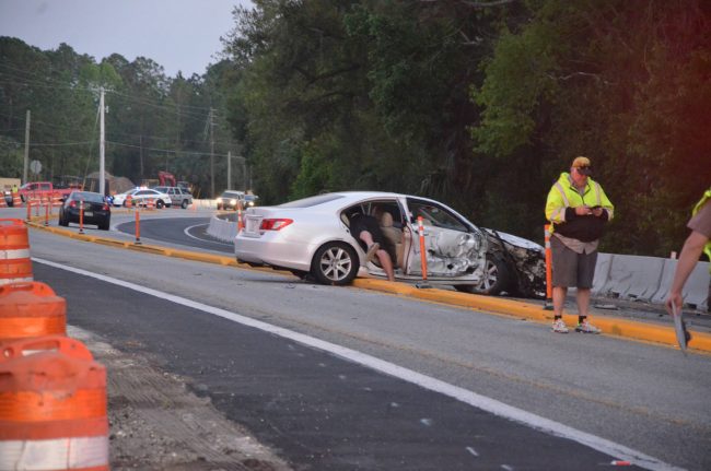 The Lexus was a distance south of the crash scene. Its occupant, seen here fetching something from the back seat, was not injured. Click on the image for larger view. (© FlaglerLive)