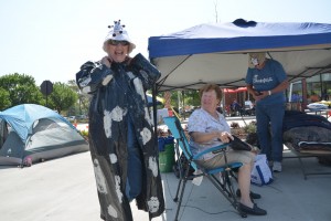 Libby Knupp, left, in her chicken attire, with Jake standing under the tent and Velma Boswell sitting near. Click on the image for larger view. (© FlaglerLive)