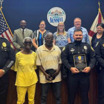 Front Row: Bunnell Police Chief David Brannon, Evelyn Cooper, Leonard Cooper, Officer Micheal Fansler, and Lieutenant Shane Groth; Back Row: Bunnell City Manager Alvin Jackson, Commissioner Tonya Gordon, Mayor Catherine Robinson, Vice-mayor John Rogers, Commissioner Tina-Marie Schultz, and Commissioner Pete Young.