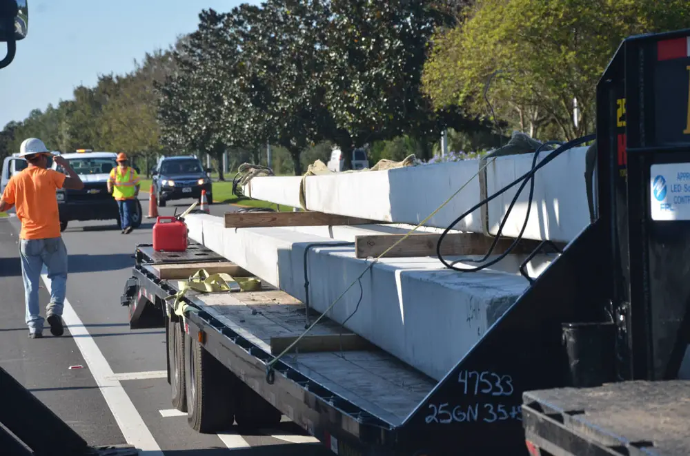 Workers with L&S Lighting getting set to plant more concrete light poles on the east side of Belle Terre Parkway near Buddy Taylor Middle School on Monday, part of the project to light up the parkway. (© FlaglerLive)