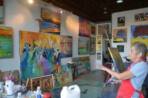 The beatifying Linda Solomon, dancing on a canvass amid a few of her works. Click on the image for larger view. (© FlaglerLive)