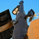 A small, black license plate recognition camera is mounted on a light pole in Boulder, Colo.
