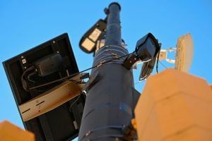 A small, black license plate recognition camera is mounted on a light pole in Boulder, Colo.