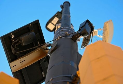A small, black license plate recognition camera is mounted on a light pole in Boulder, Colo.
