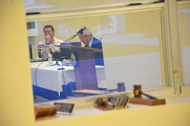 Martin Murphy, right, reflected in a commission chamber window during his interview with Bunnell's commissioners last month. His contractual demands are not resonating with commissioners. (© FlaglerLive)