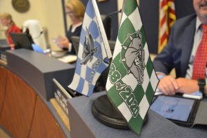 School Board member Andy Dance displayed the flags of the two high schools' Class of 2020 at a board meeting a few weeks ago. The shape of the Class of 2021 is in flux. (© FlaglerLive)