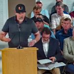 Matt Hathaway, a member of Preserve Flagler Beach and Bulow Creek, asking the Flagler Beach City Commission for some assurances about a potential land sale to preserve 153 acres around the headwaters of Bulow Creek. Ken Belshe, the developer of Sumertown, is to the right in the front row, next to attoirney Michael Chiumento. (© FlaglerLive)