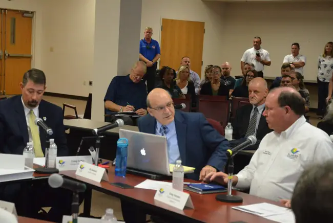 Dennis McDonald, second from left in the background, writing notes during a recent workshop on the Sheriff's Operations Center, with--at the table, from left--County Administrator Craig Coffey, County Attorney Al Hadeed, and County Commission Chairman Greg Hansen. (© FlaglerLive)