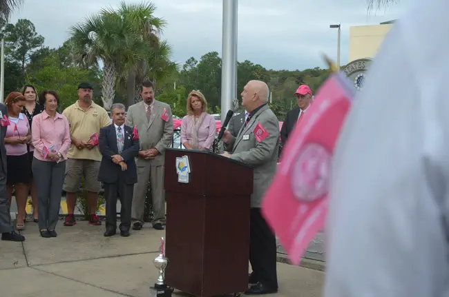 Flagler County Commissioner Frank Meeker spoke of his own battle with cancer over the last several months, as part of this morning's Pink Army flag-raising in front of the Flagler County Government Services Building. (© FlaglerLive)