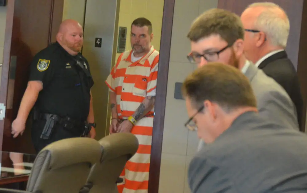Michgael Cummings entering the courtroom, with a prosecutor and defense attorneys to the right. (© FlaglerLive)