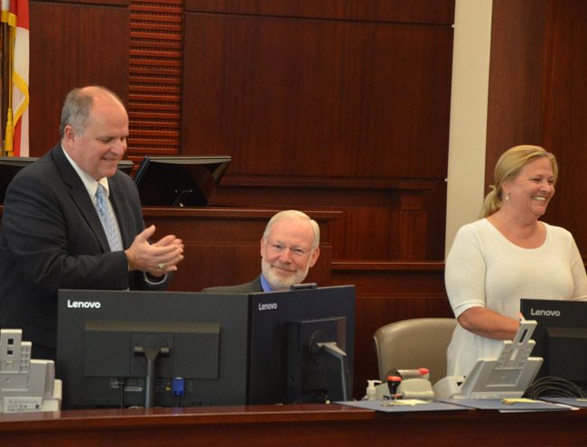 It was goodbye to Michael Greenier, center, today at the 32nd drug court graduation, as Greenier will retire from coordinating the program after serving five judges since the program's inception in 2007. He was applauded by Assistant Public Defender Bill partington, left, and Liz Williams, the now-retired Flagler Beach detective who has also always been involved in drug court. (© FlaglerLive)
