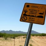 A Spanish-language sign warns migrants along the U.S.-Mexico border against explsing themselves to the dangerous elements in the desert.