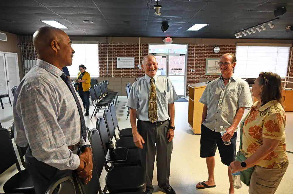 Mike Abels, center, speaking with Flagler Beach residents before the city commission meeting Thursday, with the Commission's Ken Bryan, left. (© FlaglerLive)