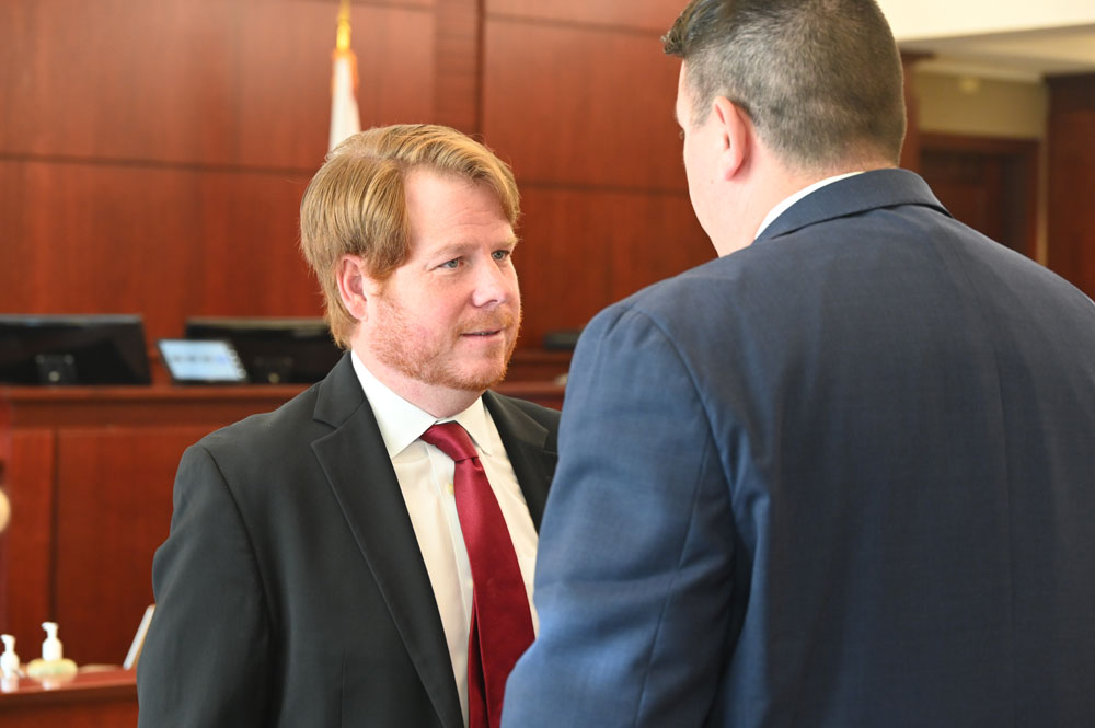Douglas Law Firm attorney Zachary Miller, one of the attorneys representing Palm Coast, speaking to Jeremiah Blocker, a partner at the firm. (© FlaglerLive)