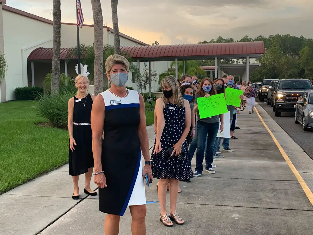 The picture tells the story: Superintendent Cathy Mittelstadt, who visited every school today, led a welcome-back line at Buddy Taylor Middle School, where every faculty member and employee and School Board member Maria Barbosa wore a mask, as per school district regulation--with the exception of School Board Chairman Janet McDonald, who has frequently denied the severity of covid-19 and is not a big mask wearer. (© FlaglerLive)