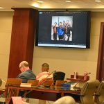 Stephen Monroe, in the striped shirt, looks at himself--right, in the image on the screen--and others holding weapons in an image he had posted to his Instagram account around the time of the killing of Noah Smith. The prosecution showed the image in court today and convinced the judge to admit it as evidence, over the defense's objection. (© FlaglerLive)