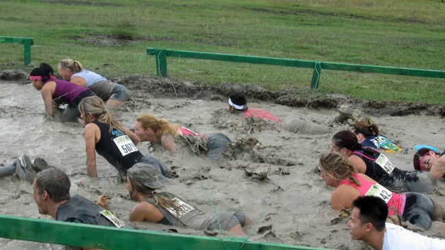 They don't call it grueling for nothing: an obstacle course requiring the contestants to crawl in mud beneath barbed wires. The author is in the pink tank top toward the right, with Priscilla Chanfrau to her right, Darci Claggett in the center of the picture, and Jane Eddy to Claggett's left, wearing No. 5079. (© Michael Eddy)