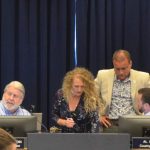 Joe Mullins, standing, right, conferring with Assistant County Attorney Sean Moylan at a meeting in June. County Administrator Jerry Cameron is to the left. Mari Davis, his assistant, is in the center. (© FlaglerLive)