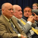 Commissioners Donald O'Brien, in the foreground, and Chairman Dave Sullivan, in the middle. Mullins, third from left, has relied on them as a shield. (© FlaglerLive)