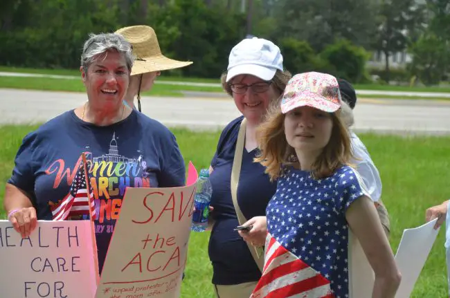 A few of today's protesters on State Road 100 by the Florida Hospital Flagler entrance: from left, Pat Ferraro, Nancy Nally, and Nally's 14-year-old daughter, Bridget. Click on the image for larger view. (© FlaglerLive)