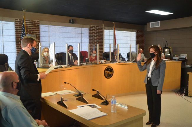 Suzie Johnston taking the oath of office, with City Attorney Drew Smith to the left and the commission looking on. (© FlaglerLive)