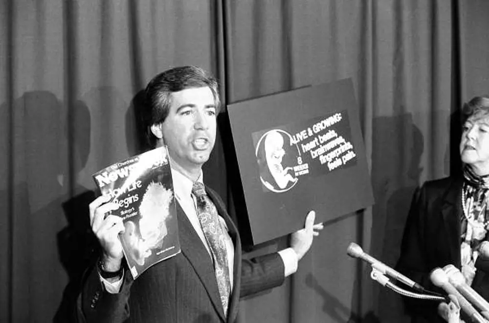 "Kenneth Conner, director-at-large for Florida Right To Life, Inc., holds up the cover of Newsweek magazine, left, and pro-life ad graphic barred from 1987 state government telephone directory. Conner held up the comparisons during a Thursday news conference at which the group announced their support of Republican Paula Hawkins for the U.S. Senate."