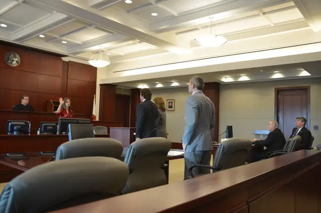 Only Dennis McDonald, the man at the center of the former case against Palm Coast, was absent as the matter of how much McDonald and his attorney will have to pay in legal fees  went before Judge Michael Orfinger Monday. Present in the courtroom, to the right, were Palm Coast City Manager Jim Landon and City Council member Bill McGuire. McDonald's attorney, Josh Knight, is in the foreground, as attorneys Debra Nutcher and Michael Chiumento were being sworn in to testify. (c FlaglerLive)