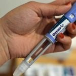 A woman takes out an Ozempic pen. More states are considering dropping GLP-1 drugs from their Medicaid programs. (Photo by Shalina Chatlani/Stateline)