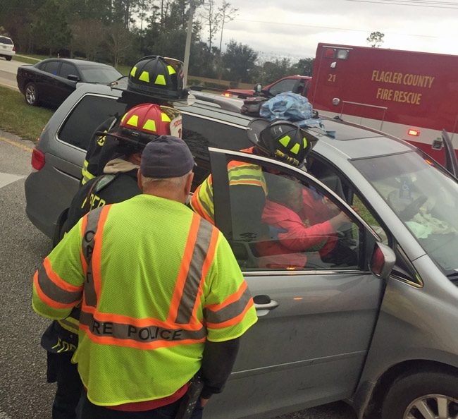 Paramedics help one of the two people injured in the crash on State Road 100 this afternoon. Both patients had leg injuries. (© FlaglerLive)