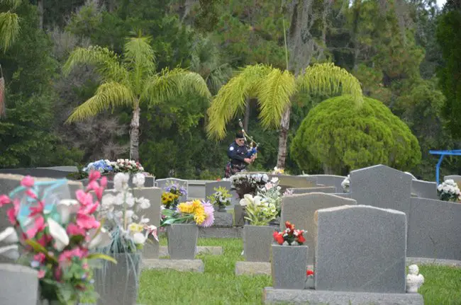 Patrick Juliano playing the bagpipes at his father's grave a few months ago, at Craig Flagler Palms cemetery. (© FlaglerLive)