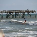 The ruin of the Flagler Beach pier was backdrop to the city's Hang 8 Dog Surfing competition last May. The City Commission on Thursday approved a mechanism to cover loans to keep the pier project moving forward--and also approved the 2024 Hang 8 competition, through a special exception. (© FlaglerLive)