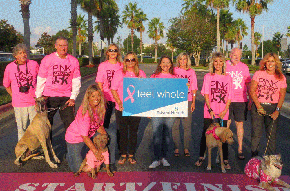 The Pink Army 5K committee, and a few friends, stand at the 5K start/finish line in front of AdventHealth Palm Coast.