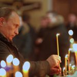 Vladimir Putin lights a candle as he attends an Orthodox Church service in 2011.